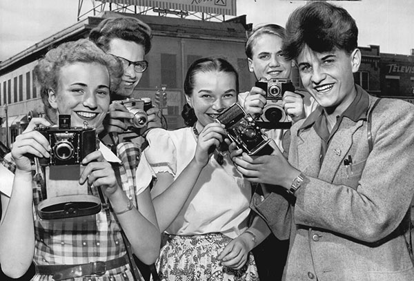 Historic image of teens holding various styles of cameras