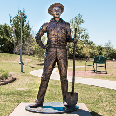 Statue of a young man wearing a hat and holding a shovel
