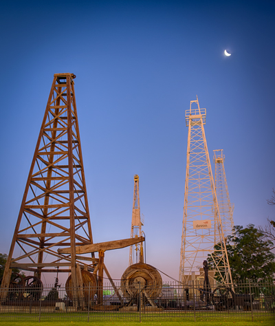 The exhibit's wooden oil derricks and equipment at twilight