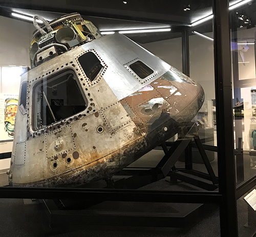 The Apollo Command Module on display. The module is a rounded metal vessel with a few small windows.
