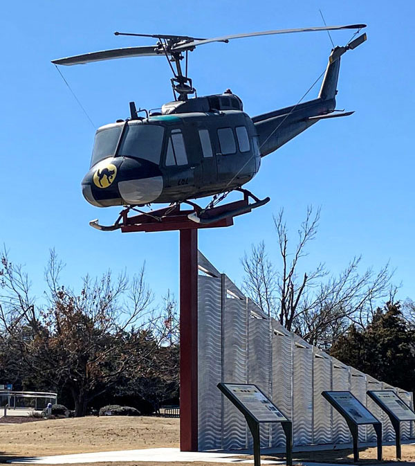 Outdoor exhibit featuring a helicopter on the highest point of an arcing metal divider