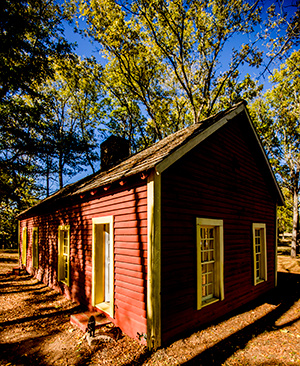 The small cabin-style sutler's store at Fort Towson Historic site is red with yellow trip