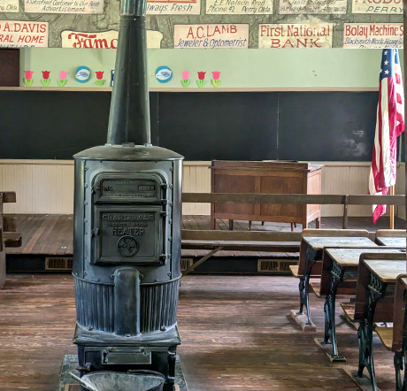 A Ben Franklin stove sits among desks at the Rose Hill Schoolhouse.