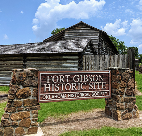 The Fort Gibson Stockade buildings behind a sign reading 'Fort Gibson Historic Site.'