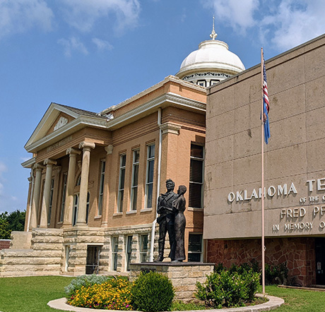 Two story brick building designed in the Second Renaissance Revival architectural style. Prominent columns hold up a wide portico framing the entrance to the building.