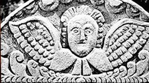 A folk art–style carving of an angel on a grave marker.