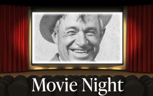 Will Rogers depicted on a large movie screen.