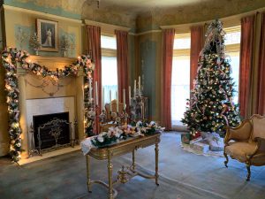 A Christmas tree, candles, and a fireplace garland decorate the parlor room at the Henry and Anna Overholser mansion.