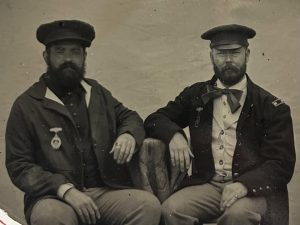 A tintype photo of Kenneth Sivard and T. S. Akers wearing Civil War Era uniforms with medals. They are seated