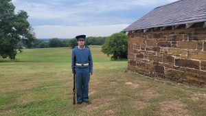 Seth Goff wearing an Infantry uniform and holding a musket at Fort Gibson.