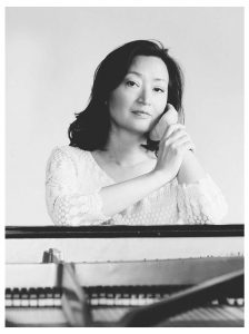 Dr. Hyunsoon Whang sitting at a grand piano