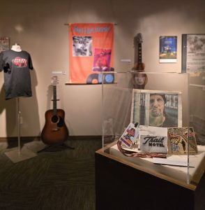 An exhibit hall with guitars, posters, and musician artifacts on display.