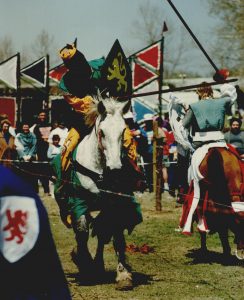 Two individuals dressed as knight, joust each other on horseback.