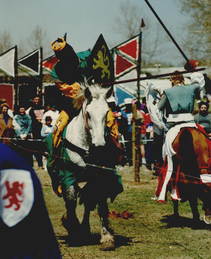 Two individuals dressed as knight, joust each other on horseback.