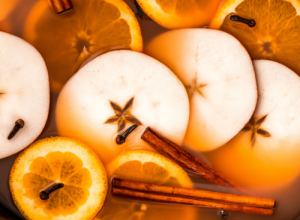 Apple slices, cinnamon sticks, and cloves float in a pot warming apple cider.