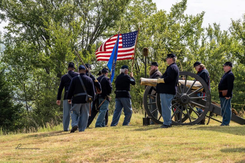 Men dressed in Union Civil War uniforms perform an artillery salute.