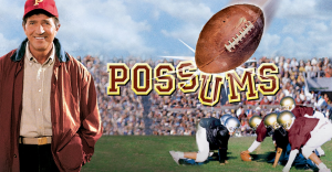 A coach standing in front of a field of football players kicking a football.