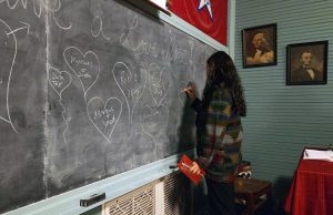 A young lady drawing hearts on a chalkboard.