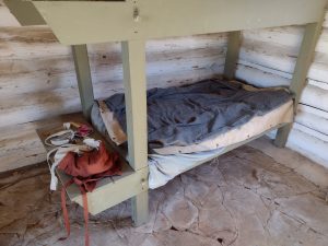 A lower bunk in the Fort Gibson Stockade with blankets, clothing, and supplies laid out.