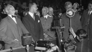 Will Rogers at a microphone entertaining President Franklin Delano Roosevelt.