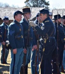 Soldiers dressed in Union blues stand at attention.