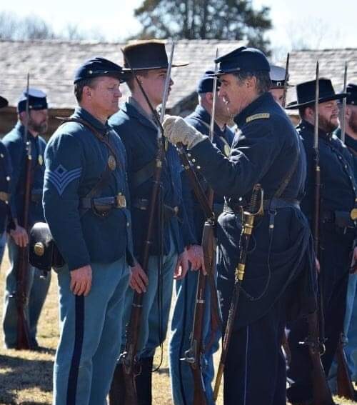 Soldiers dressed in Union blues stand at attention.