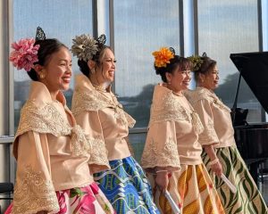 A group of women in traditional Asian clothing perform at the History Center.