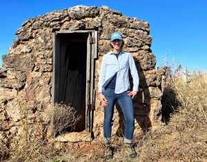 Kristina Wycoff stands outside a tiny jail structure made of stone.