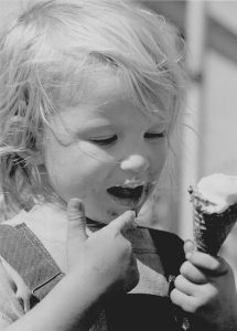A girl eats an ice cream cone.