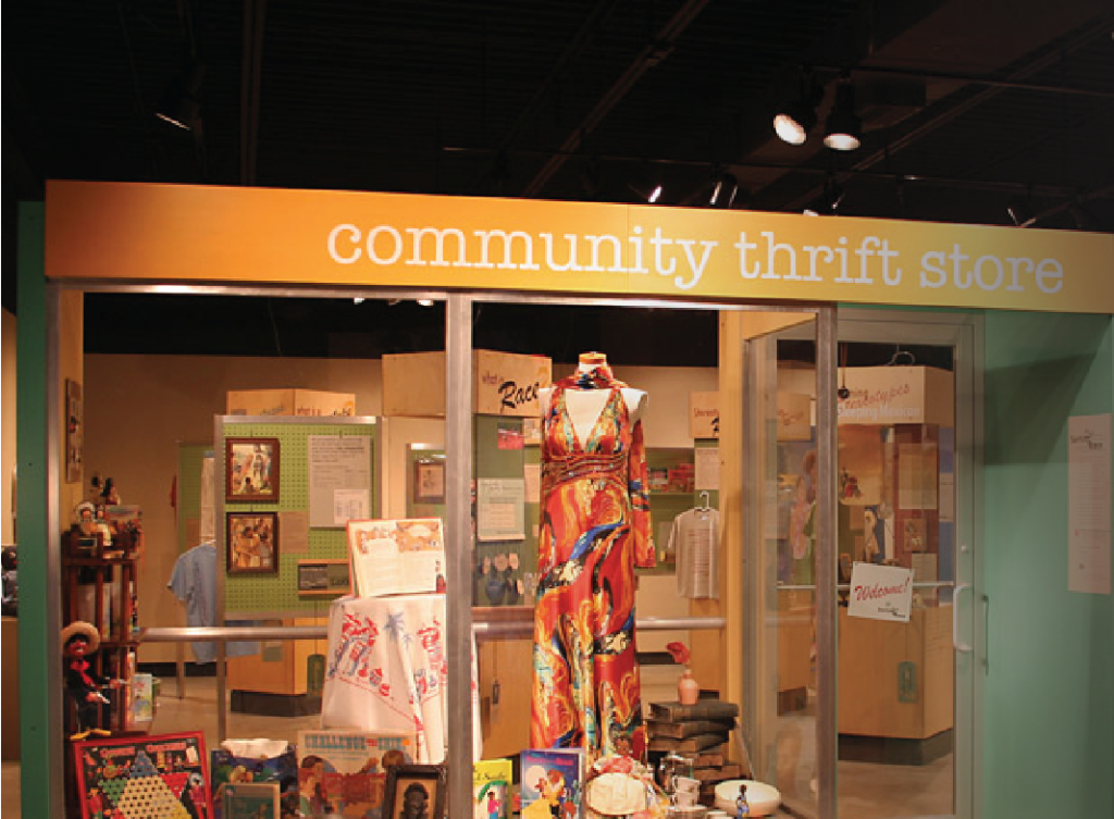 An exhibit room designed as a thrift store with clothing and artifacts displayed in the front window.