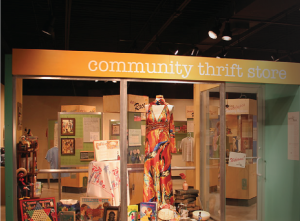 An exhibit room designed as a thrift store with clothing and artifacts displayed in the front window.