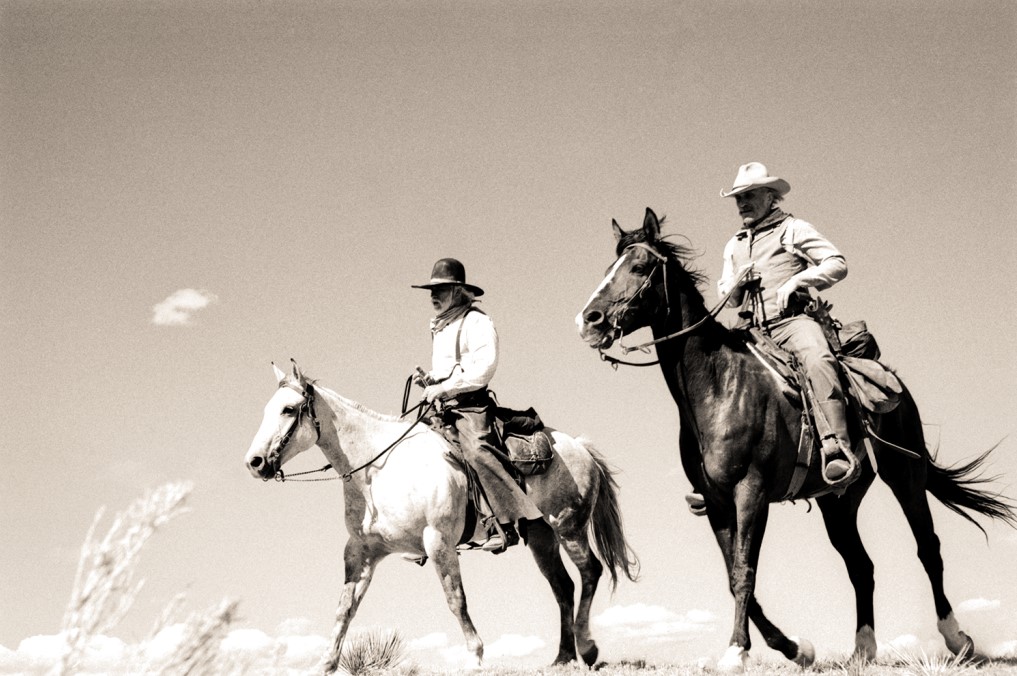 Robert Duvall and Tommy Lee Jones ride on horseback in Western gear during the filming of the movie Lonesome Dove.