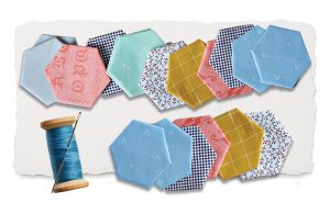 Fabric hexagons of different colors and patterns and a spool of thread.