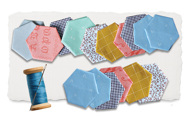 Fabric hexagons of different colors and patterns and a spool of thread.