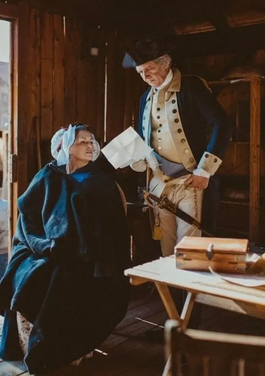 Dan and Kelly Shippey dressed as Martha and George Washington confer about a handwritten letter.