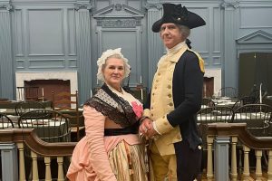 George and Martha Washington reenactors stand together in Colonial costumes.