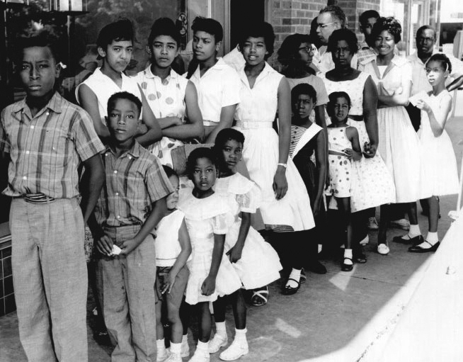 Several students stand on the sidewalk during a 1960 civil rights demonstration