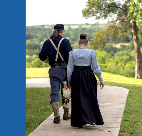 The annual report cover features a two historical interpreters in period dress outdoors.