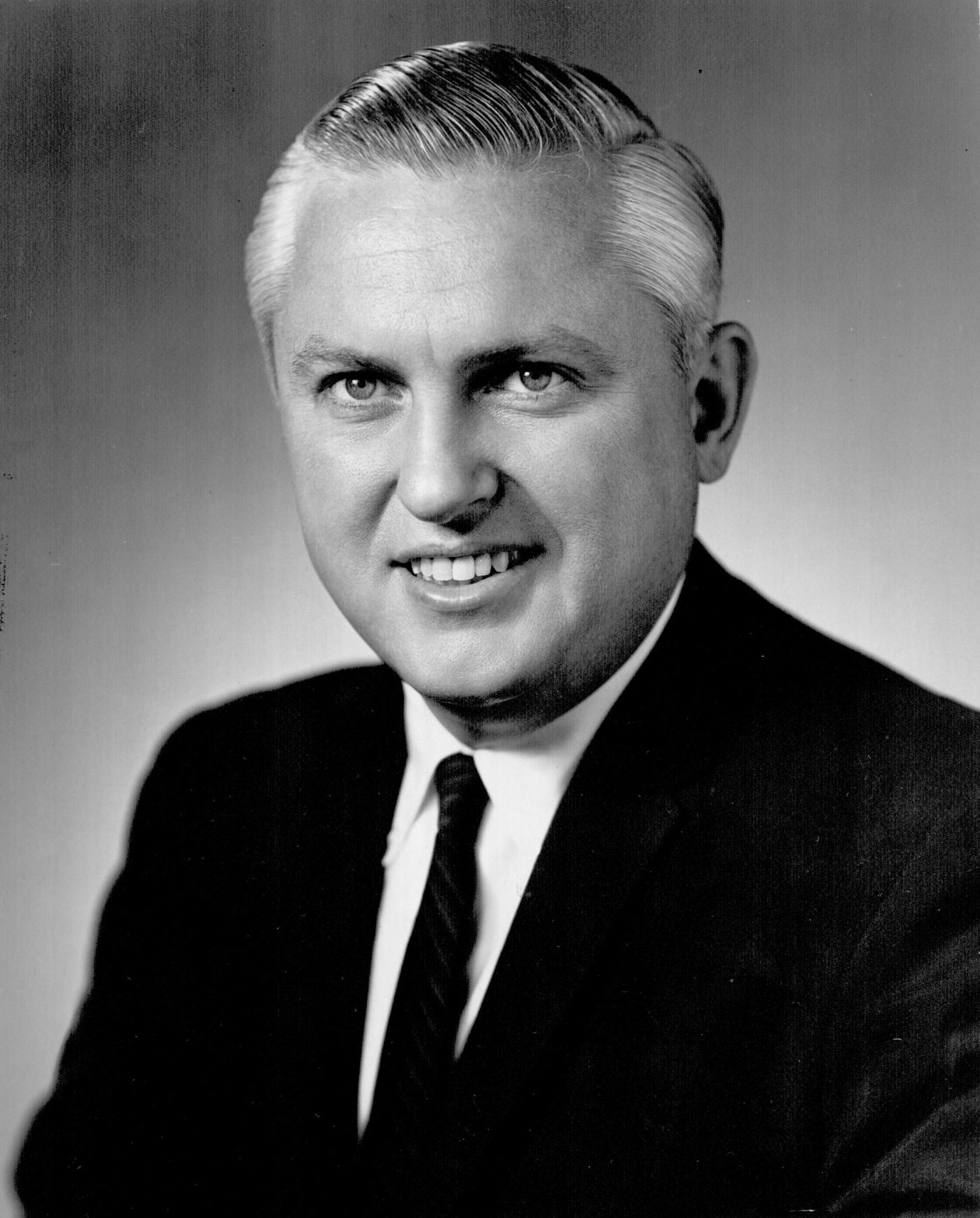 A portrait of Governor David Hall looking directly at the camera with a small smile. He wears a dark suit and tie.
