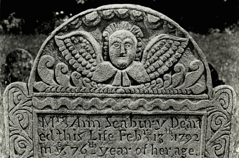 A folk art–style carving of an angel on a grave marker.