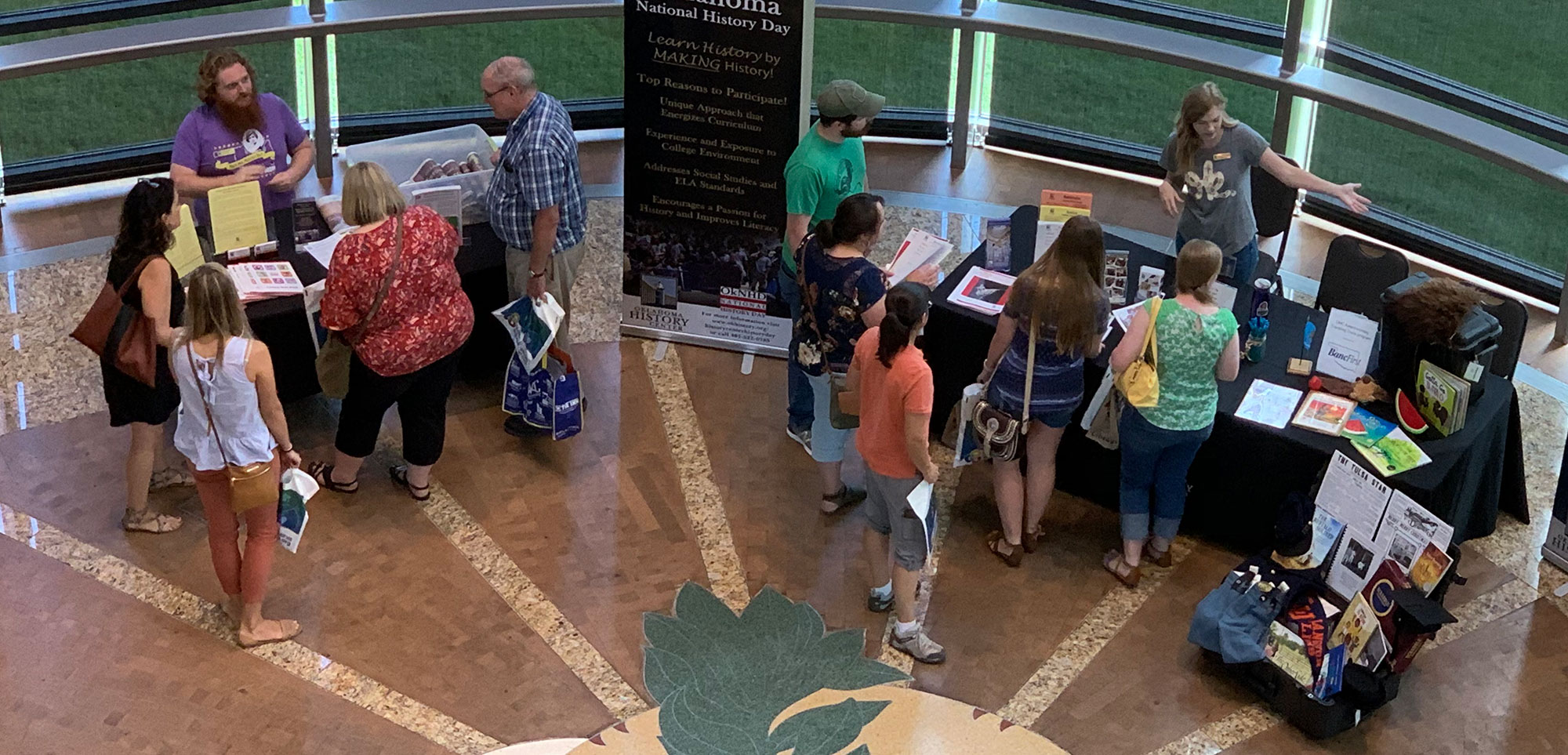 A small crowd of people view History Day booths and speak with History Center staff