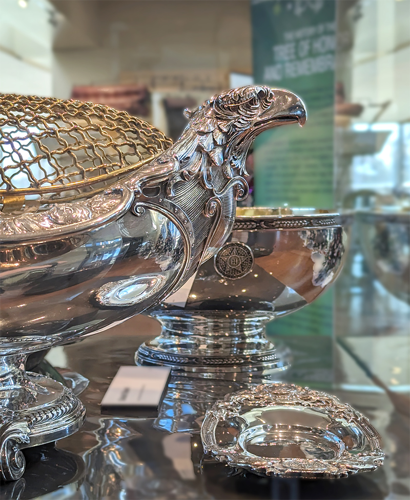 A large centerpiece dish featuring the head of a bald eagle on each end and a mesh cover, a salad bowl decorated with the state seal and wheat patterns, and a small ornate dish.