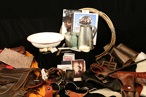 Assorted books, a rope, a holster, spurs, chaps, and other items in the Cowboy trunk
