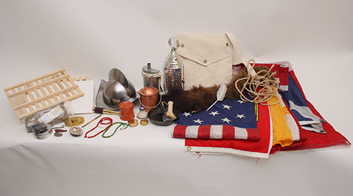 Assorted items from the Explorers trunk including flags, a canvas haversack, beads, a lantern, and a Spanish-style helmet.