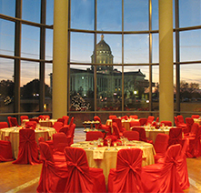 Tables and chairs in the History Center atrium. The capitol at sunset is visible through the window.