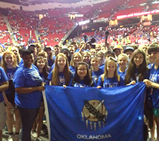 A large group of students hold the Oklahoma state flag.