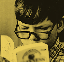 Young boy with glasses engrossed in a book