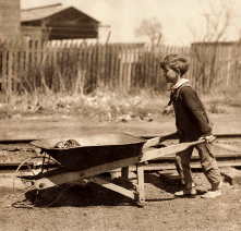 A small box pushes a wheelbarrow as seen in the child labor exhibit