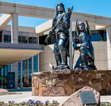 Bronze statue of two armed Apache warriors, which stands at the Oklahoma History Center entrance.