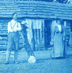 A blue-tinted cyanotype of a man and women in front of a log cabin